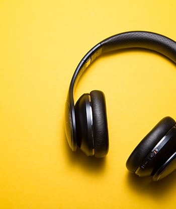 Black over-ear headphones with cushioned pads on a bright yellow background.